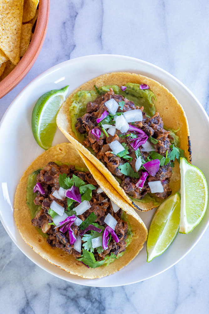 vegan black bean tacos on a plate with toppings and chips