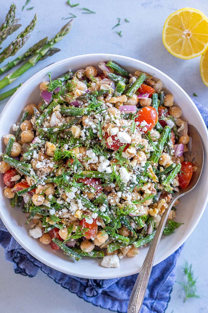 A big bowl of roasted asparagus salad topped with feta cheese