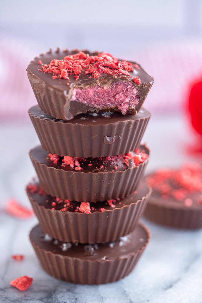 a stack of chocolate strawberry coconut cups with a bite taken out of one