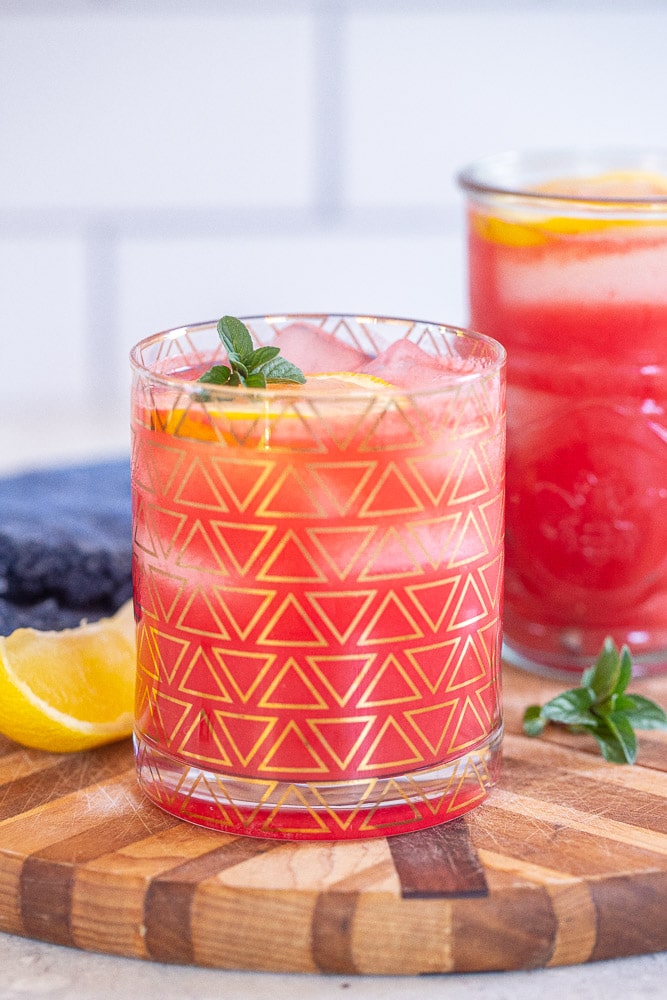 watermelon lemonade in a glass with lemon wedge and mint
