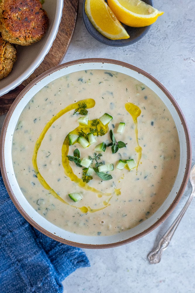 A bowl of vegan tzatziki sauce with fresh herbs and olive oil