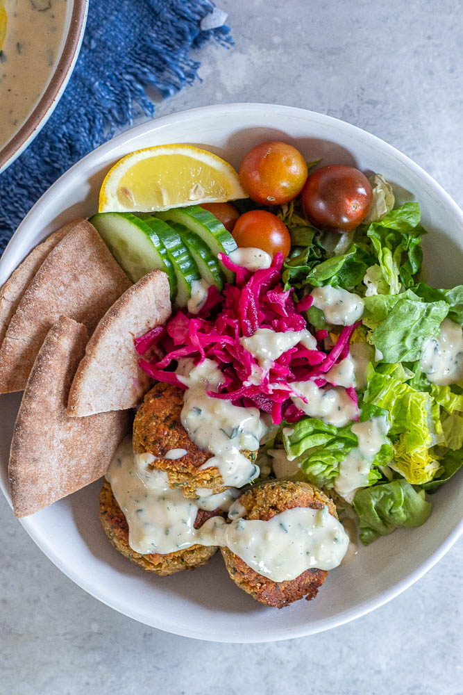 tzatziki sauce in a bowl with pita bread, falafel and vegetables