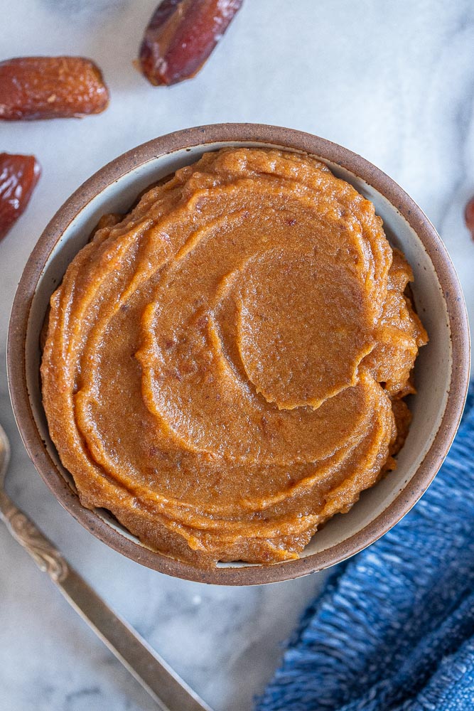 A bowl of date paste with dates around it