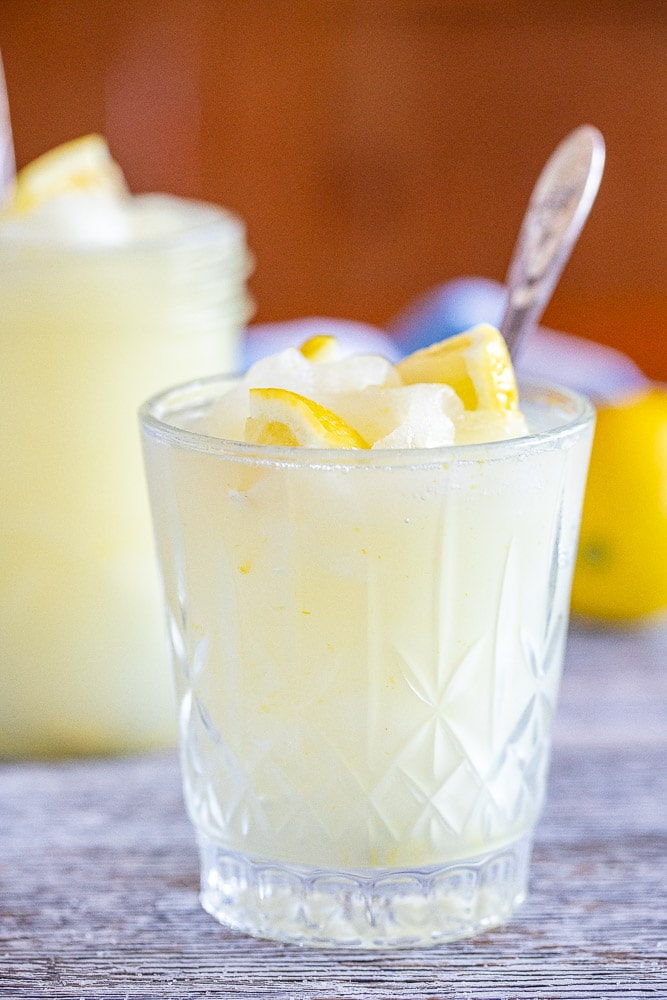 glass of frozen lemonade with fresh lemon chunks in it