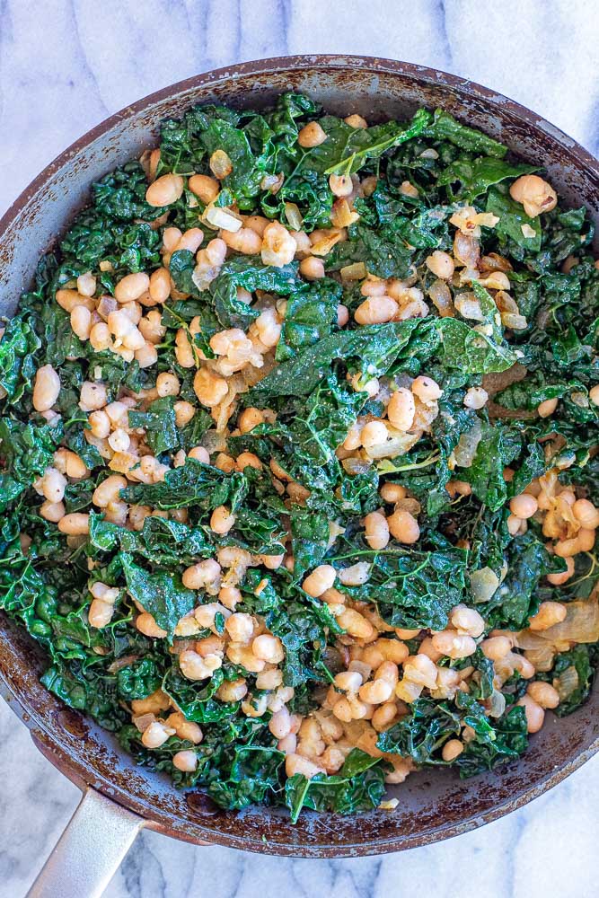 garlicky kale in a pan with white beans and lemon