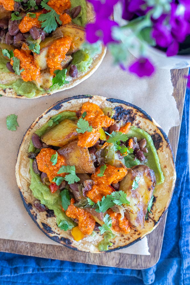 spicy potato tacos with black beans and romesco sauce topped with cilantro