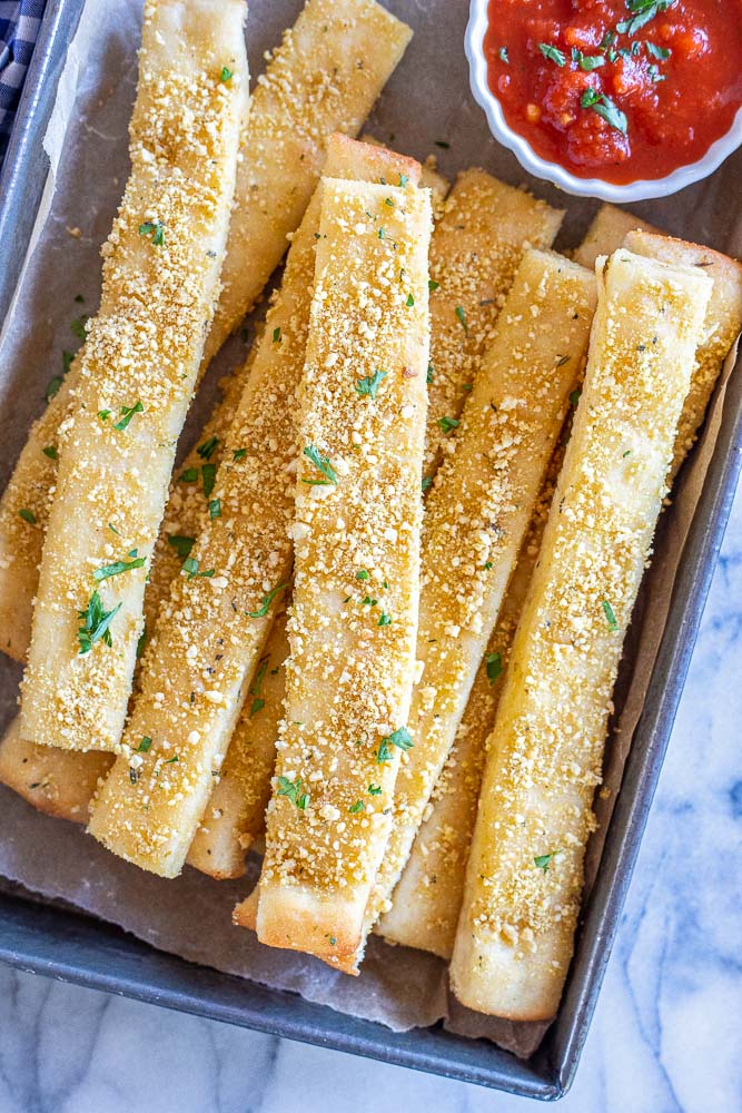 vegan bread sticks on a pan with marinara sauce