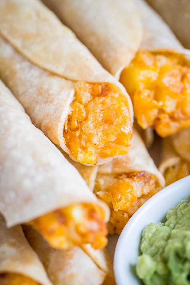 close up of a plate of cheesy potato taquitos