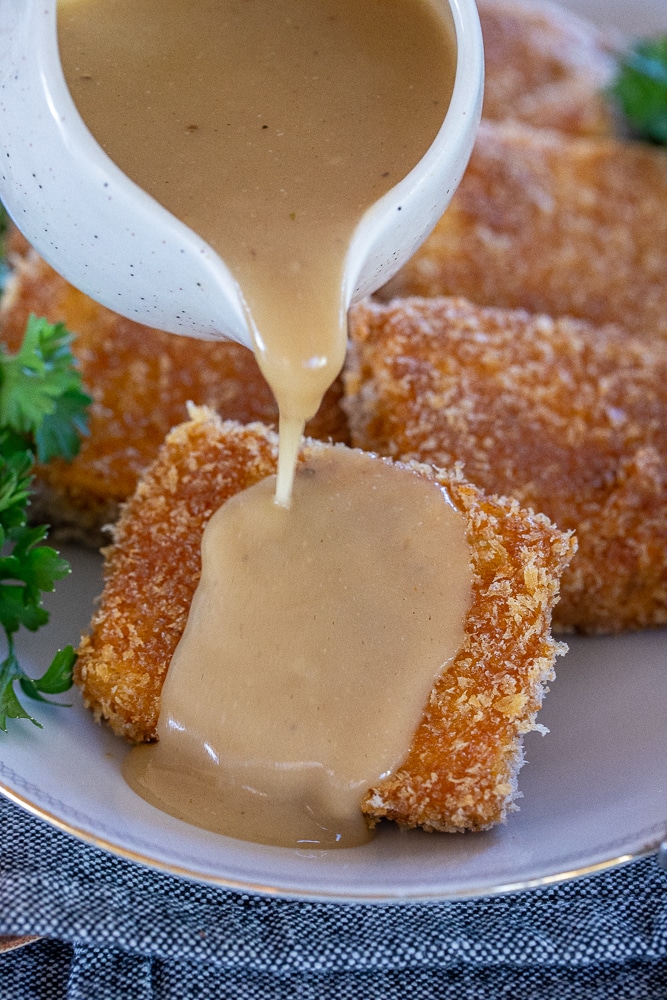 vegan gravy being poured over a crispy tofu steak
