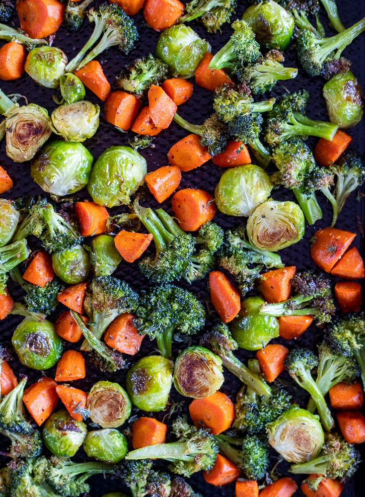 baking tray full of roasted broccoli, carrots and Brussels sprouts