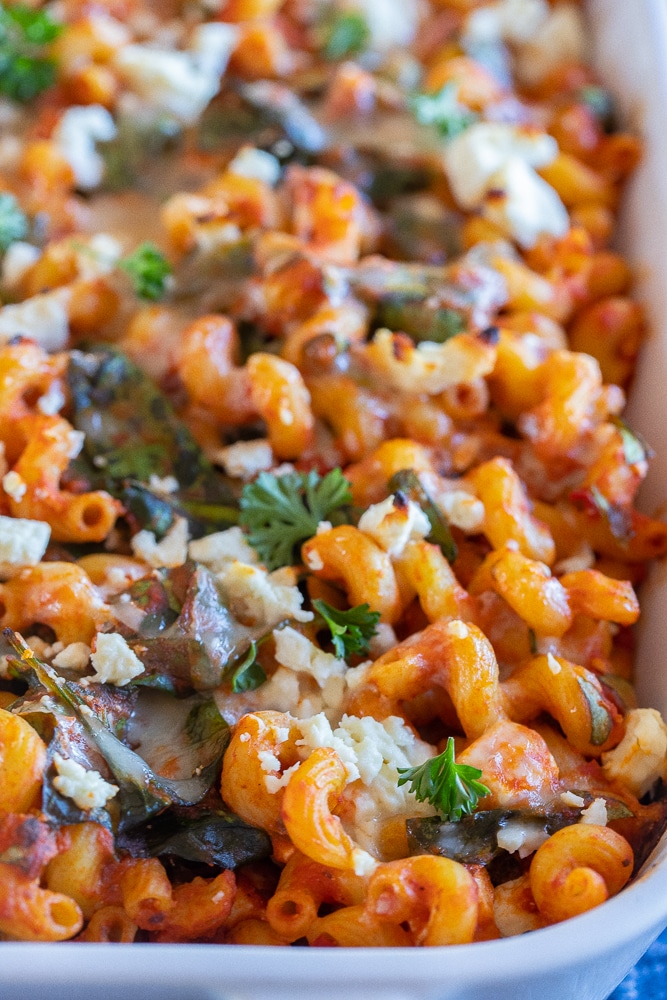 close up of spinach feta baked pasta in a pan with melted cheese