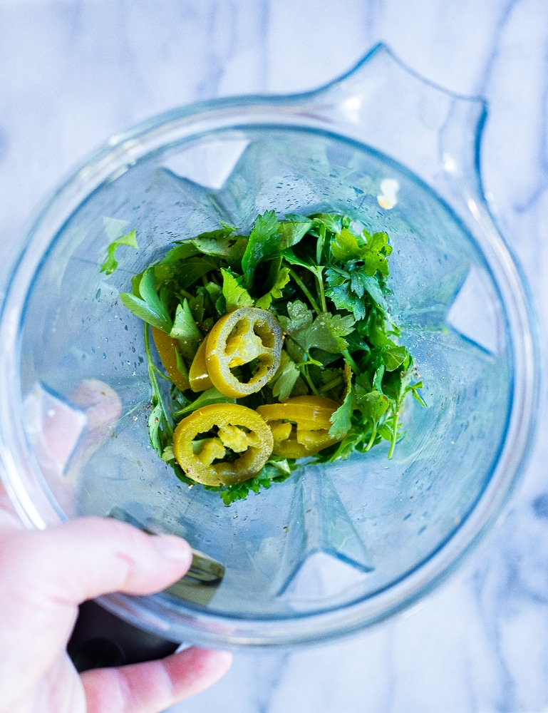 showing how to make this amazing green tahini sauce with the ingredients in a blender