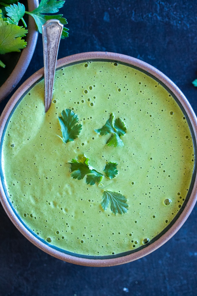 big bowl of green tahini sauce with a spoon in it