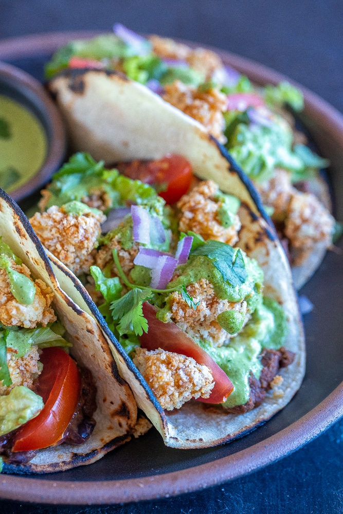 close up of a crispy cauliflower taco with green tahini sauce