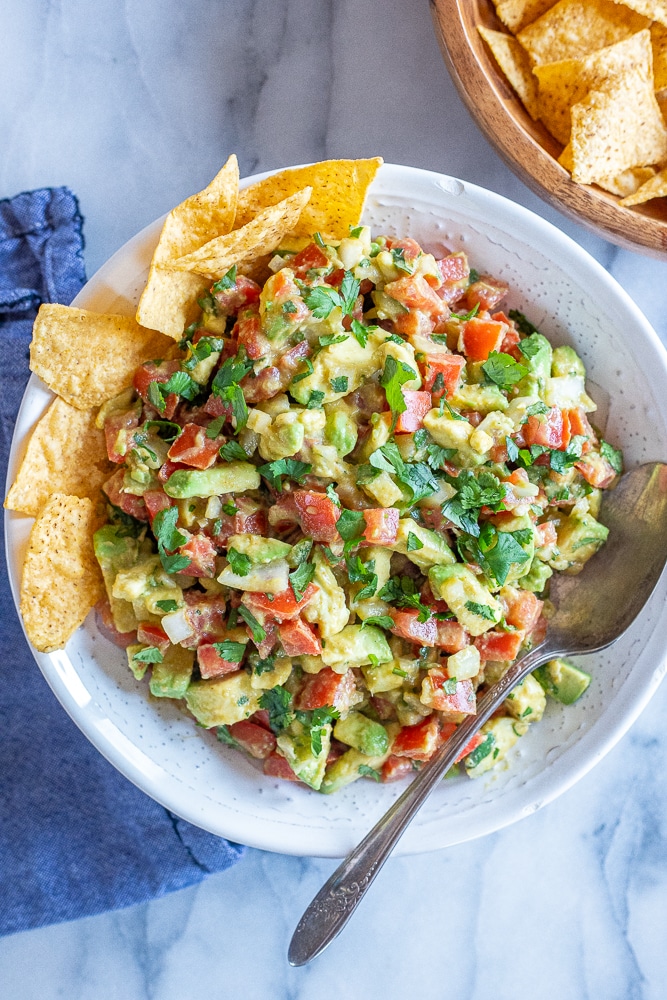 a big bowl of the best avocado salsa with chips and a spoon