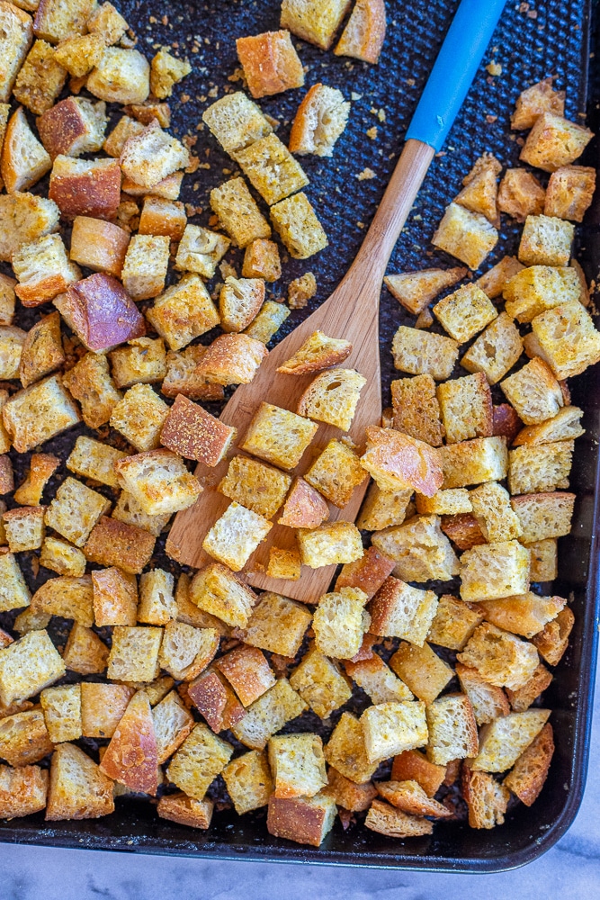 a tray of baked homemade croutons with a spatula