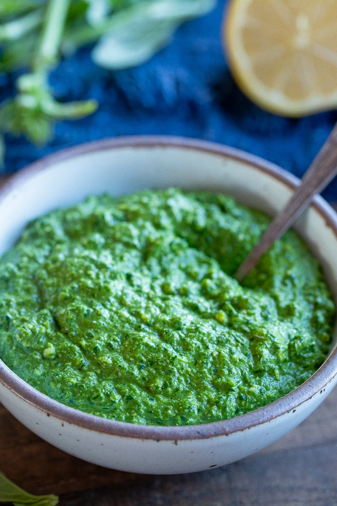 bright green vegan pesto sauce in a bowl with a spoon