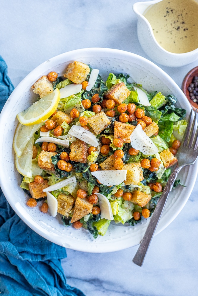 bowl of vegan Caesar salad with dressing and a blue napkin