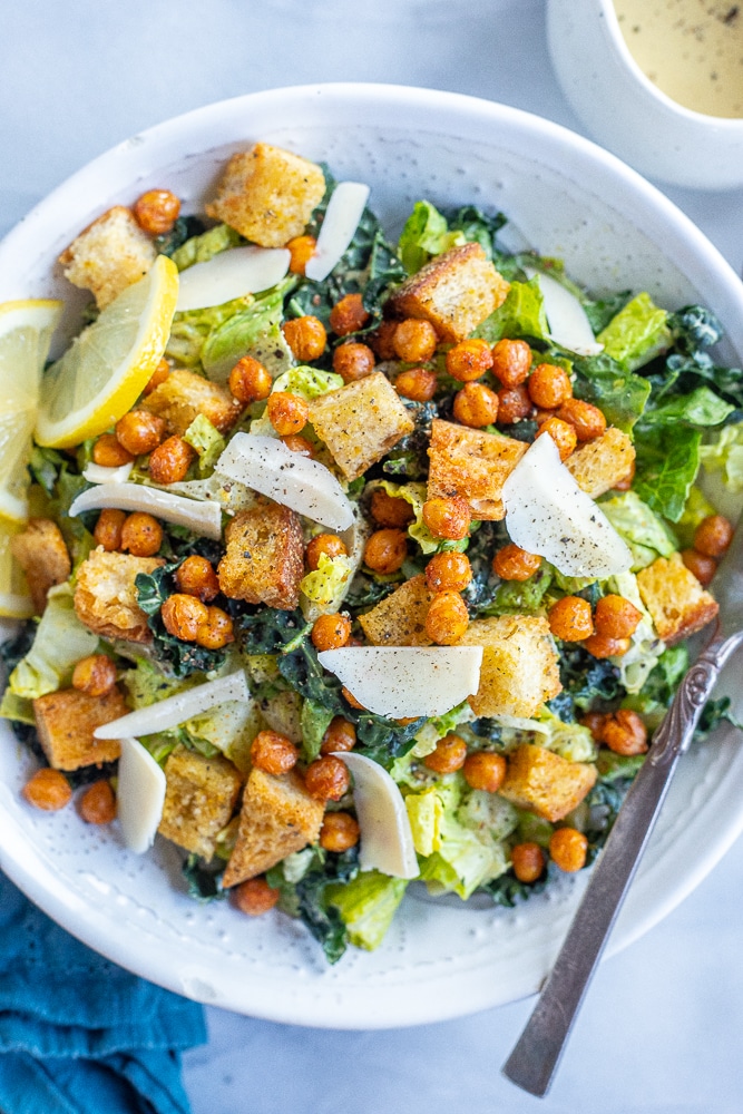 the best vegan Caesar salad in a bowl with croutons, parmesan cheese and lemons