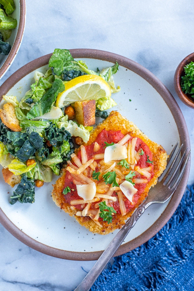 vegetarian chicken parmesan on a plate with salad and a fork