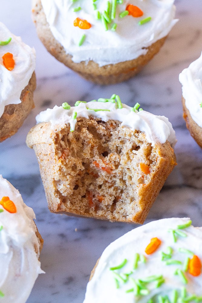 carrot cake muffins on a cutting board with a bite taken out of it