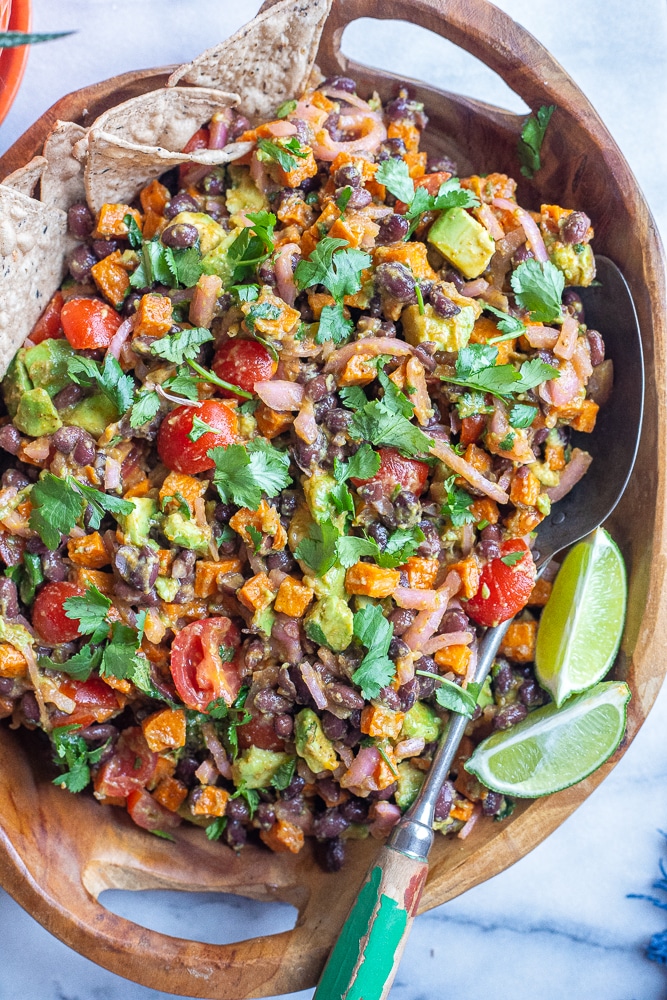 chipotle roasted sweet potato salad in a wooden bowl with chips and a spoon