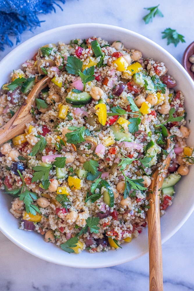 large bowl of mediterranean quinoa salad with two wooden spoons