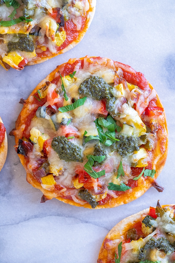 close up of a tortilla pizza recipe with roasted veggies and pesto sauce