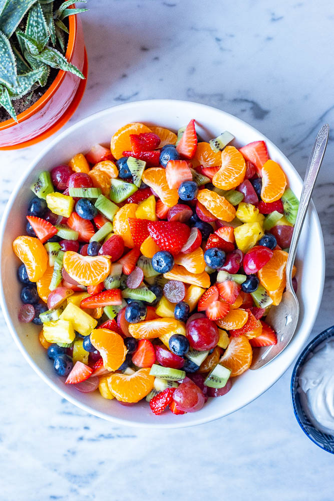 Big bowl of rainbow fruit salad with a spoon