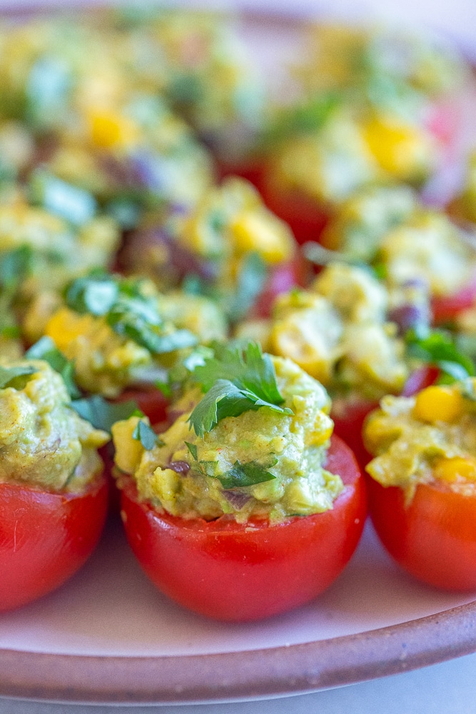 close up of a guacamole stuffed tomato with cilantro on top