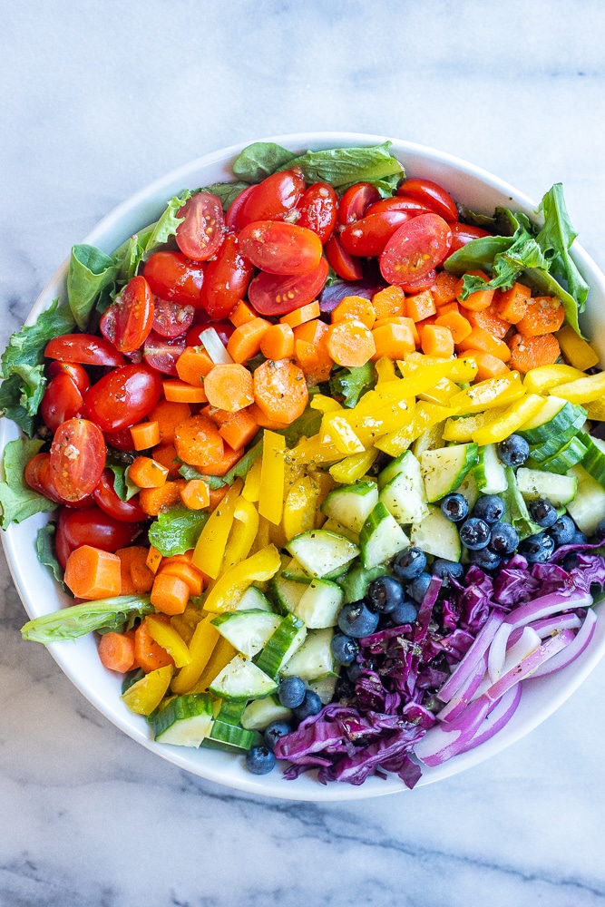 rainbow veggie salad in a bowl with dressing on top
