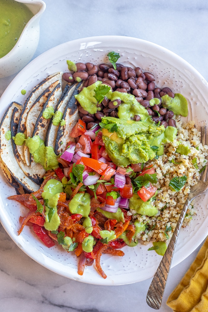 vegan fajita bowls with avocado sauce in a bowl with tortillas