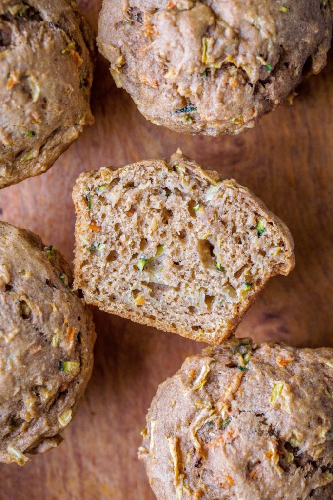 zucchini apple carrot muffins on a cutting board cut in half