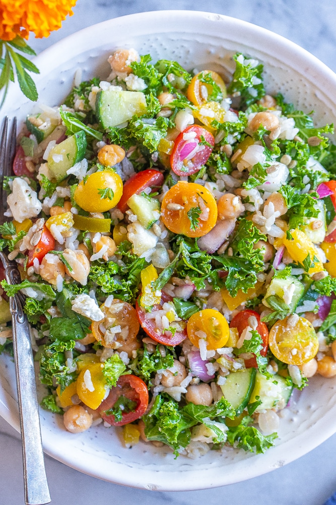 close up of rice salad with chickpeas and kale in a bowl with a fork