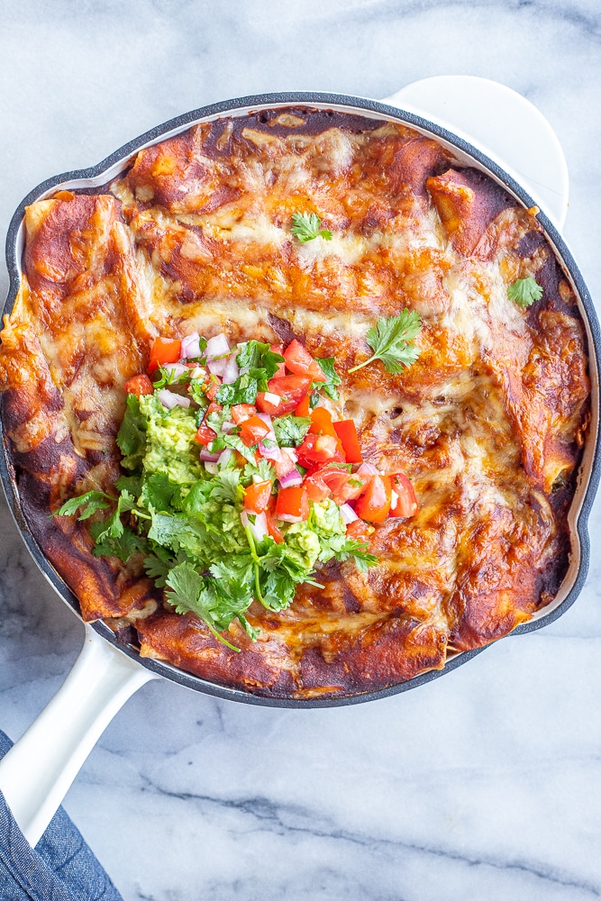 pan of cheesy zucchini enchiladas with guacamole and pico