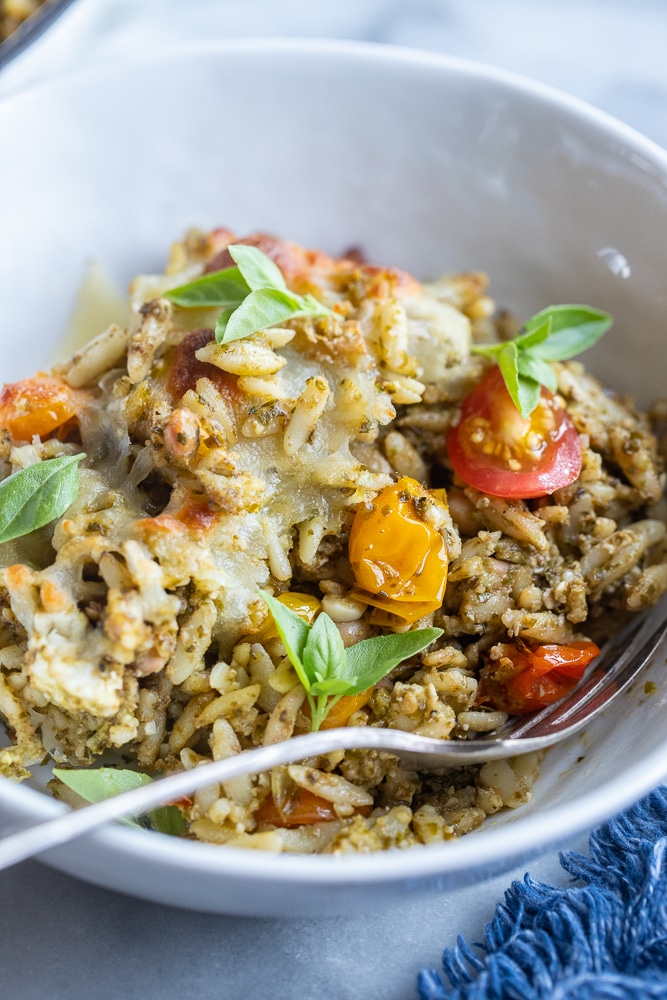 bowl of baked pesto orzo with cherry tomatoes