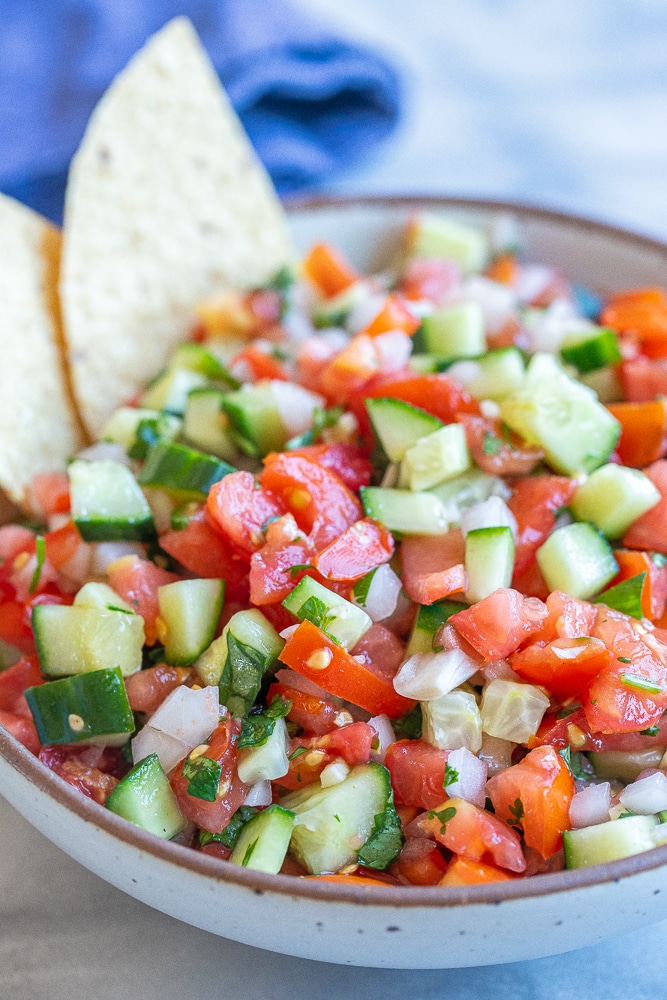 close up of chunky cucumber salsa recipe in a bowl with chips