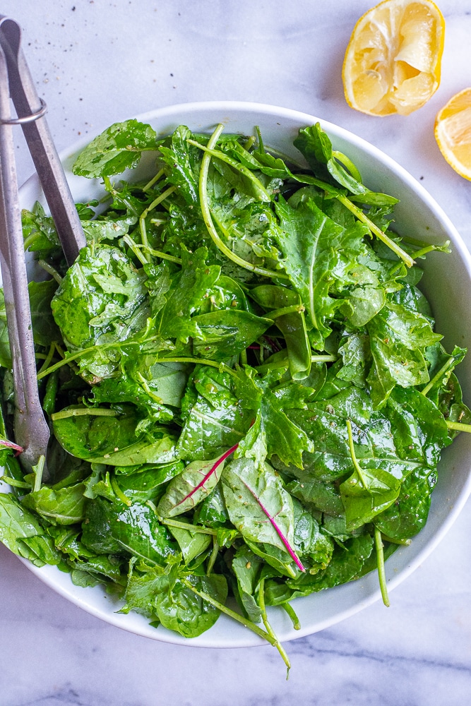 spring mix salad in a bowl with lemons