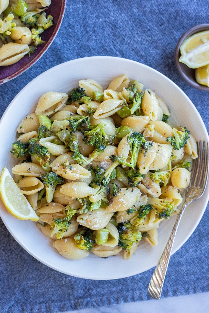 garlic parmesan pasta with roasted broccoli recipe in a bowl with a lemon slice