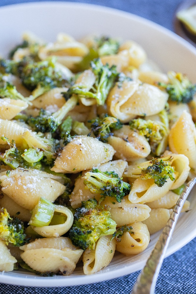 close up of a bowl of garlic parmesan pasta with broccoli and lemon