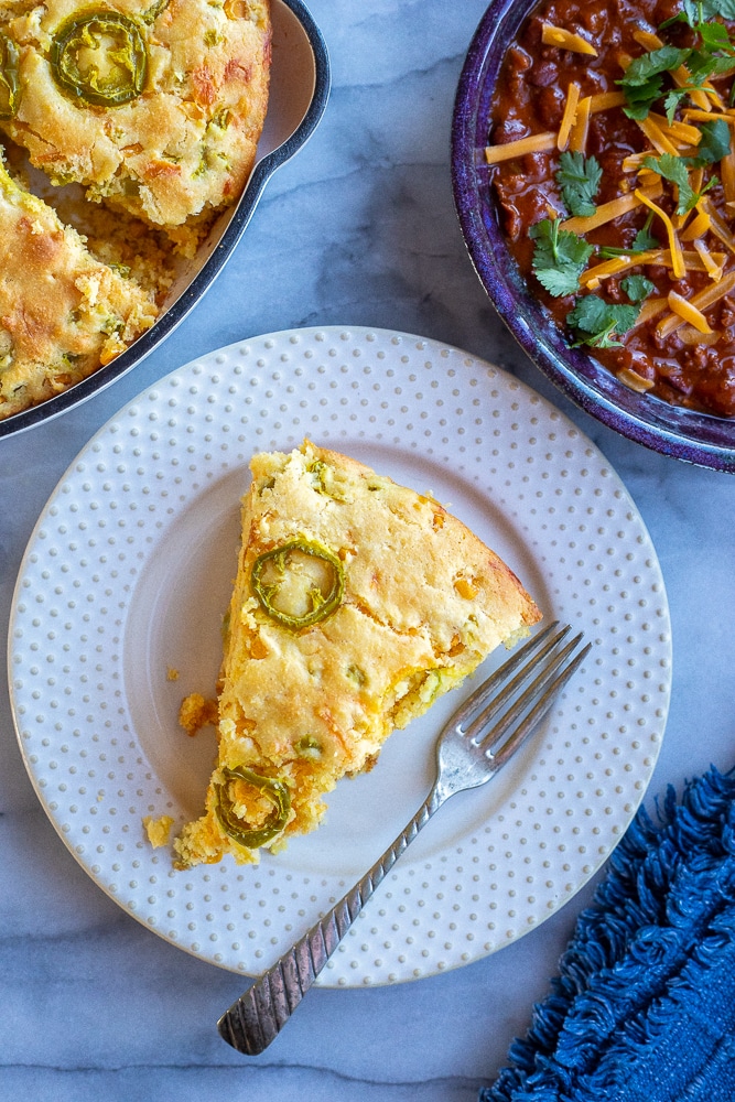 slice of pickled jalapeno cheddar corn bread on plate with chili