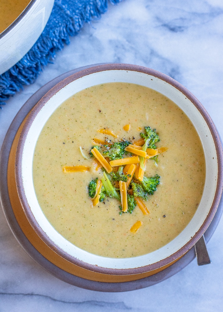 veggie packed creamy broccoli cheddar soup in a bowl with garnishes