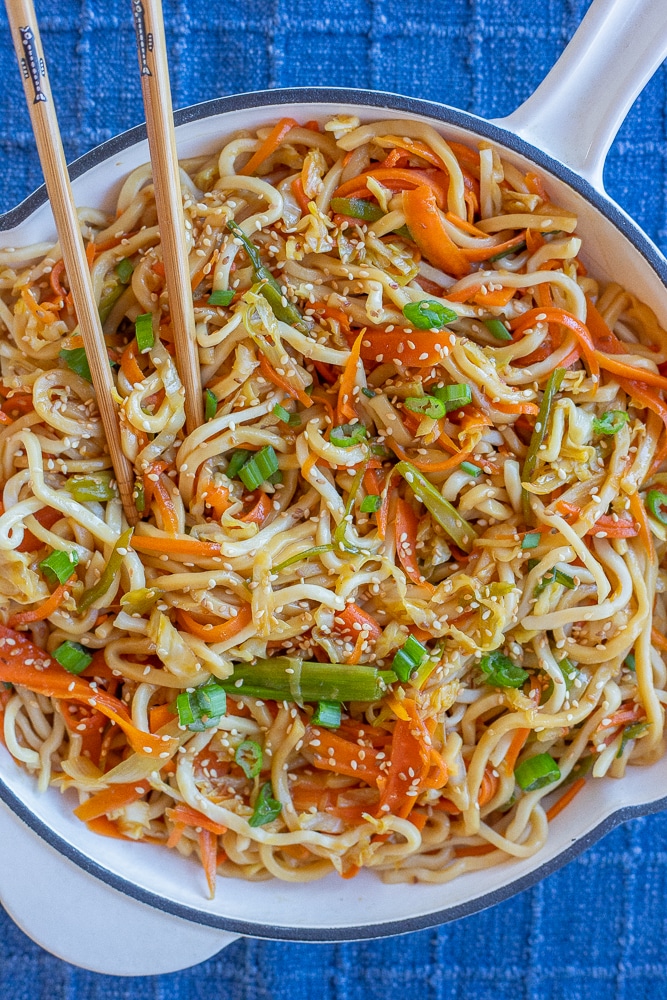 stir fry noodles with cabbage and carrots in a pan with chopsticks