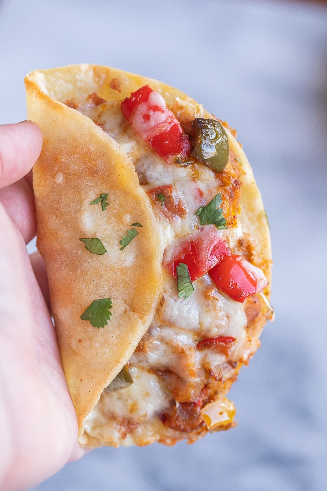 a hand holding a close up crispy baked fajita taco