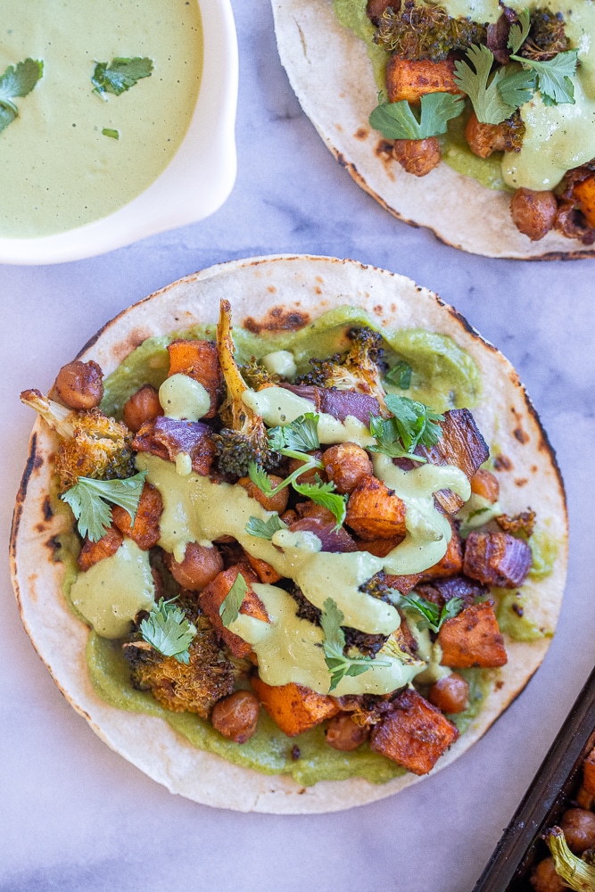 Roasted Sweet Potato Broccoli and Chickpea Tacos with green tahini sauce on a plate