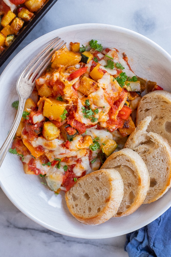 bowl of sheet pan polenta and vegetable bake with bread