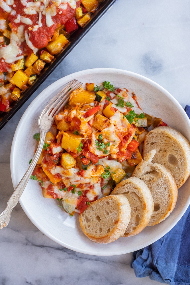 Sheet Pan Polenta Vegetable Bake in a bowl with a fork