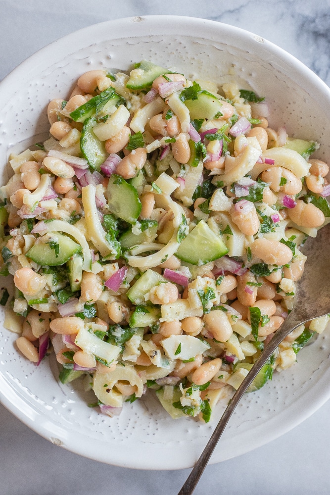 big bowl of lemony hearts of palm and white bean salad with a spoon