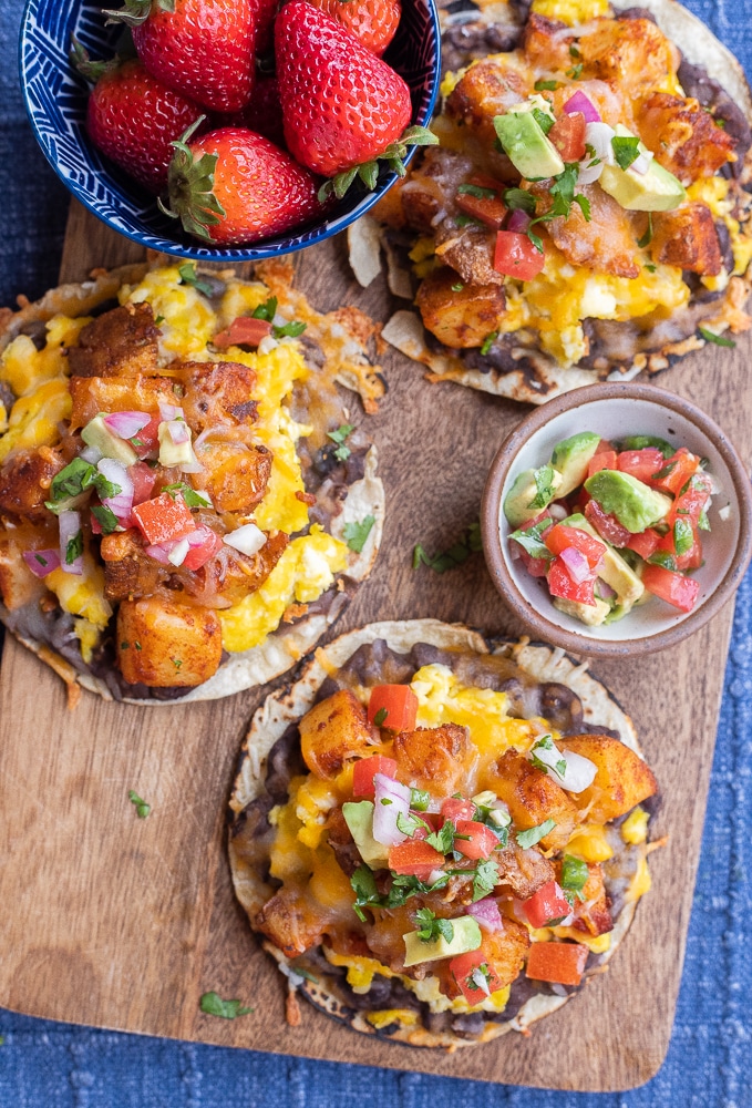 breakfast potato tacos on a cutting board with avocado salsa and strawberries
