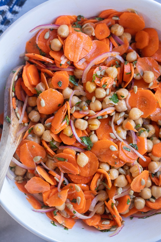 close up of a bowl of carrot and chickpea salad with an orange maple dressing